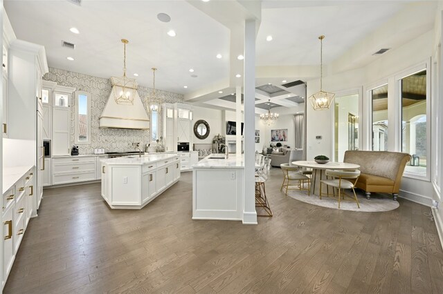 14132 Flat Top Ranch Rd, Austin, TX 78732 - kitchen with a large island with sink, custom exhaust hood, a chandelier, dark wood-type flooring, and recessed lighting