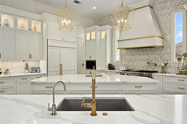 kitchen with pendant lighting, paneled built in refrigerator, custom exhaust hood, and white cabinets