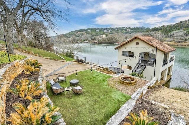 view of yard with a balcony, a water view, and an outdoor fire pit