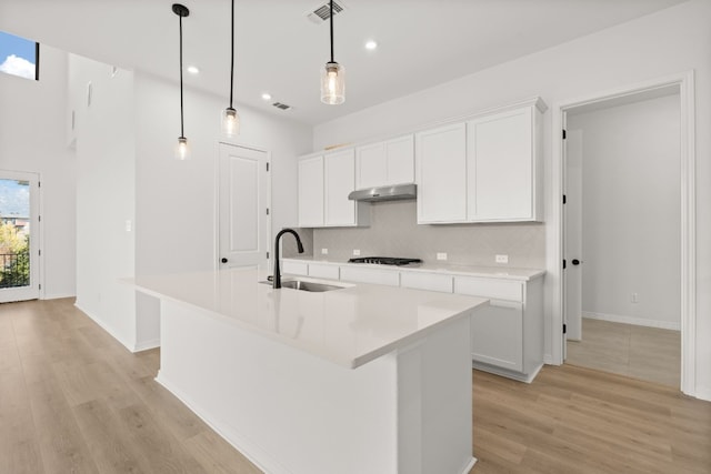 kitchen featuring white cabinetry, sink, hanging light fixtures, and an island with sink