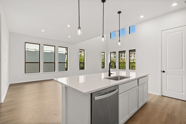 kitchen featuring sink, decorative light fixtures, dishwasher, white cabinetry, and an island with sink