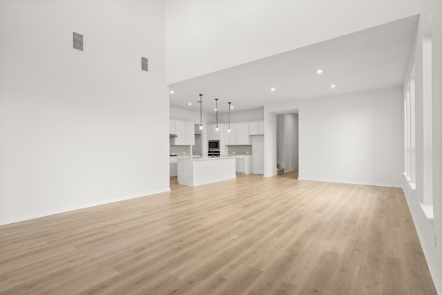 unfurnished living room featuring light hardwood / wood-style floors and a high ceiling