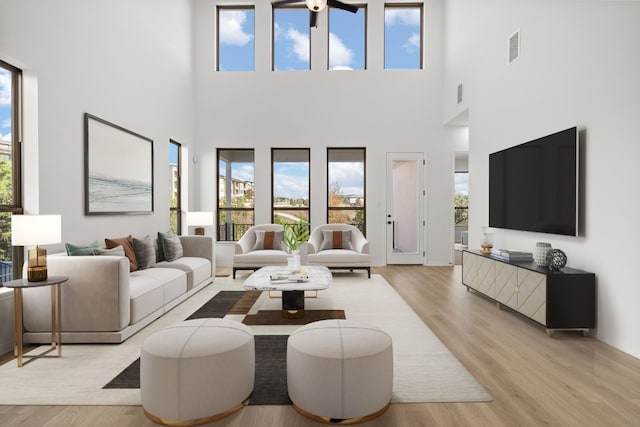 living room featuring a high ceiling, light hardwood / wood-style floors, and plenty of natural light