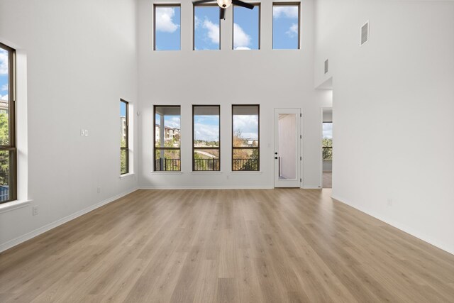 unfurnished living room with light hardwood / wood-style floors and a high ceiling