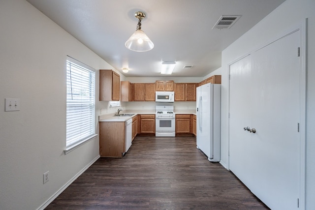 kitchen with sink, dark wood-type flooring, hanging light fixtures, and white appliances