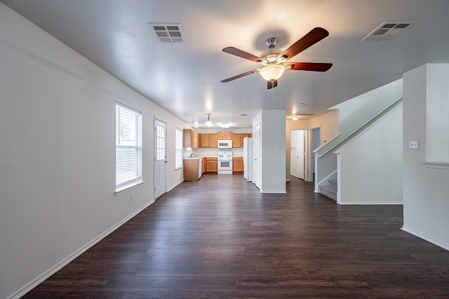 unfurnished living room with ceiling fan and dark hardwood / wood-style flooring