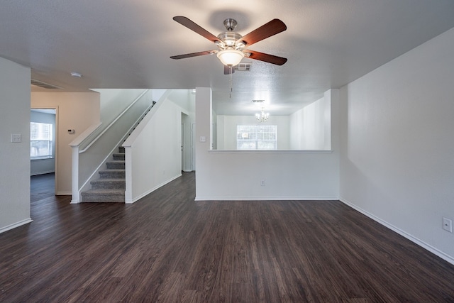 unfurnished living room with ceiling fan with notable chandelier and dark hardwood / wood-style floors