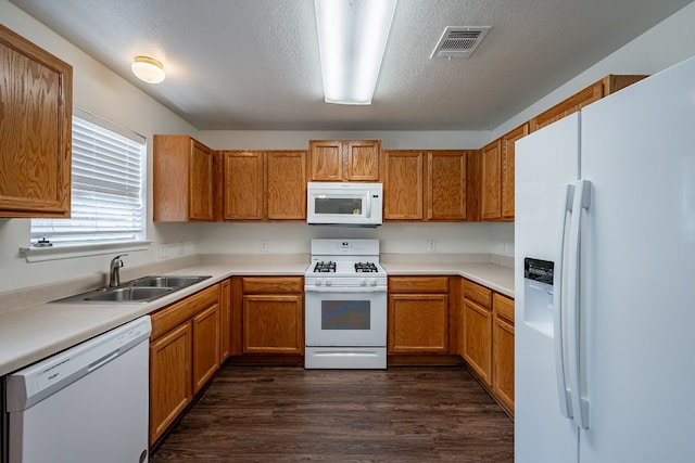 kitchen featuring white appliances, a textured ceiling, dark wood-type flooring, and sink