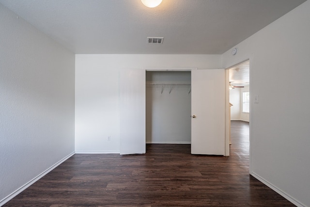 unfurnished bedroom with a closet and dark hardwood / wood-style flooring