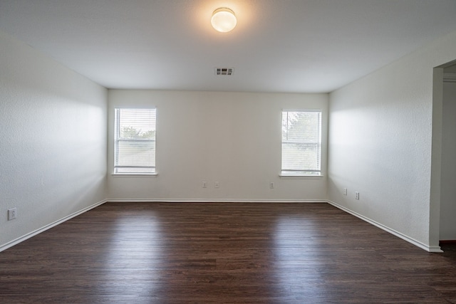 spare room with dark wood-type flooring and plenty of natural light