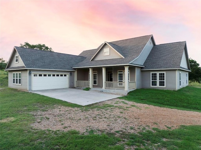 view of front of property featuring a yard, a garage, and a porch