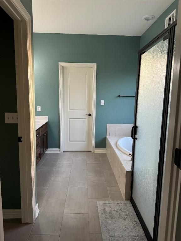 bathroom with vanity, tile patterned flooring, and a relaxing tiled tub