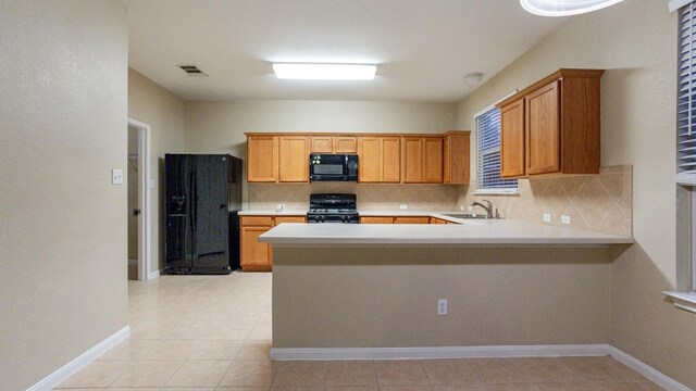 kitchen featuring sink, decorative backsplash, light tile patterned floors, and black appliances