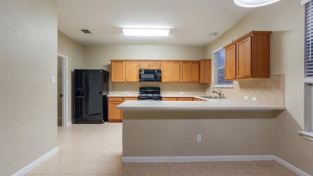 kitchen featuring a sink, visible vents, light countertops, black appliances, and tasteful backsplash