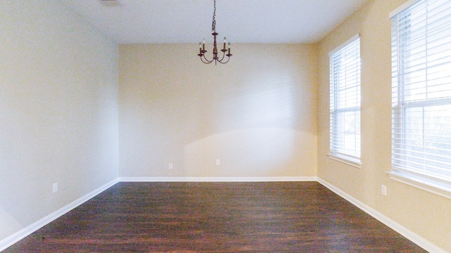 empty room with a chandelier and hardwood / wood-style flooring