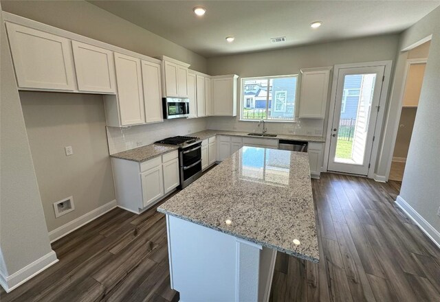 kitchen featuring dark wood-type flooring, white cabinetry, tasteful backsplash, and stainless steel appliances