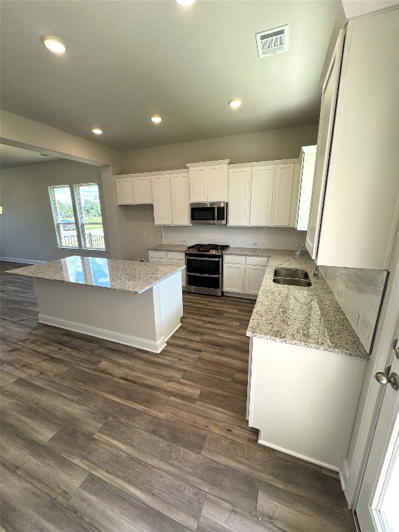 kitchen with white cabinets, stainless steel appliances, light stone countertops, and a kitchen island