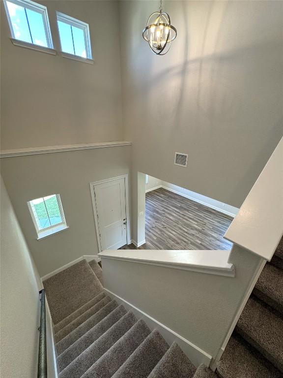 stairway with a notable chandelier, plenty of natural light, visible vents, and baseboards