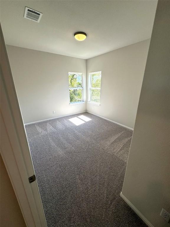 unfurnished room with carpet, visible vents, and baseboards