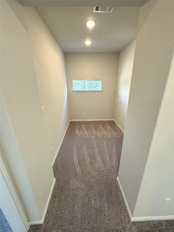 spare room featuring carpet, visible vents, and baseboards