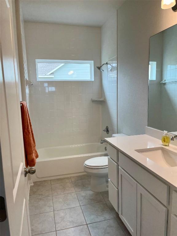 bathroom with tile patterned flooring, shower / bathing tub combination, vanity, and toilet