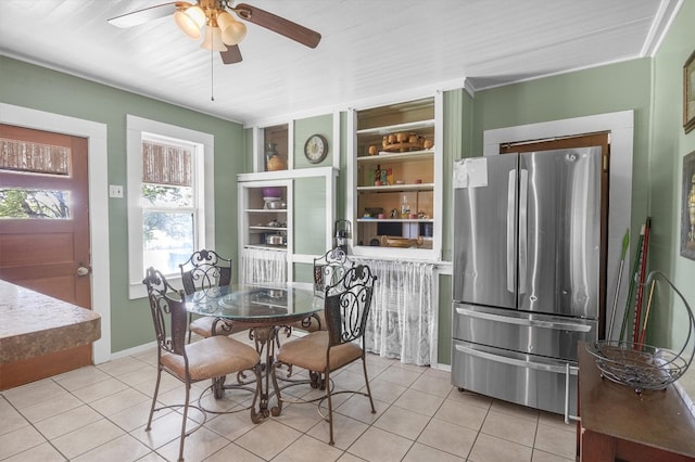 tiled dining room featuring crown molding, built in shelves, and ceiling fan