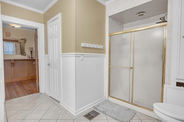 bathroom featuring toilet, a shower with door, tile patterned flooring, and crown molding