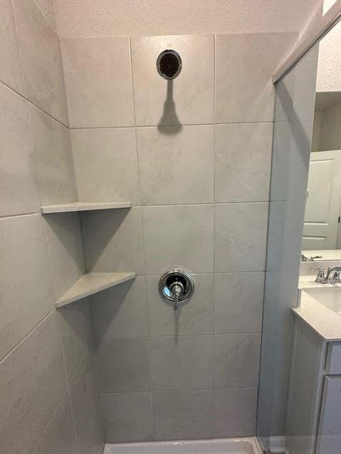 bathroom with vanity and tiled shower