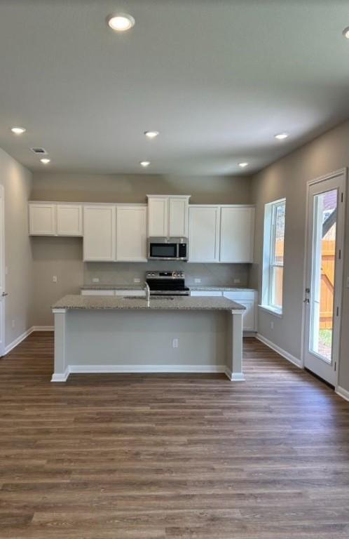 kitchen featuring stove, white cabinets, dark hardwood / wood-style floors, and a kitchen island with sink