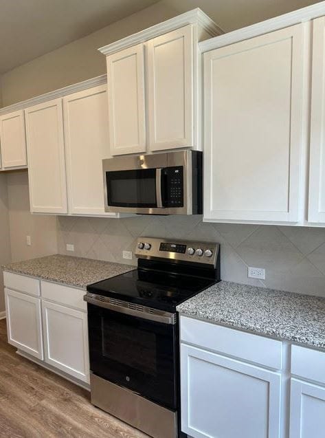 kitchen featuring decorative backsplash, appliances with stainless steel finishes, light wood-type flooring, and white cabinets