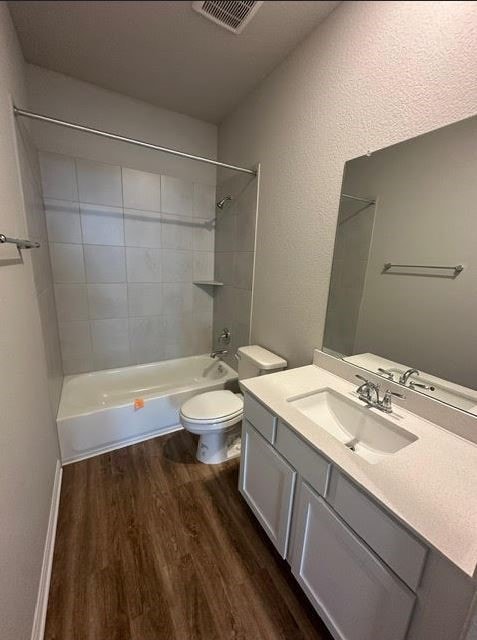 full bathroom with toilet, hardwood / wood-style floors, vanity, and tiled shower / bath