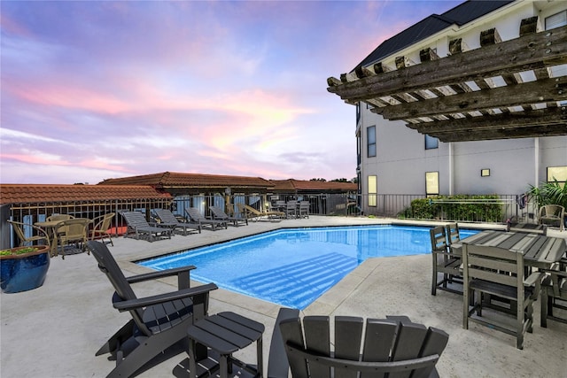 pool at dusk with a pergola and a patio