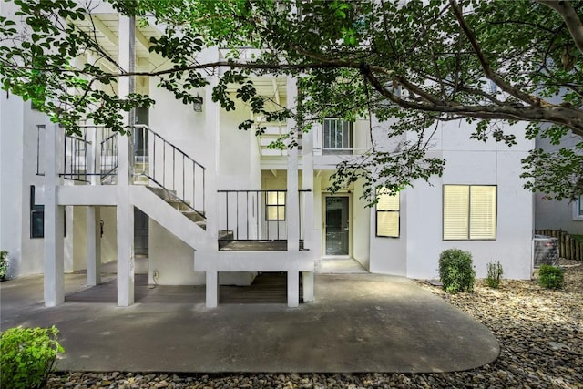 back of property featuring stucco siding, a patio, cooling unit, and stairway