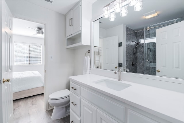 bathroom with wood-type flooring, vanity, ceiling fan, toilet, and a shower with door