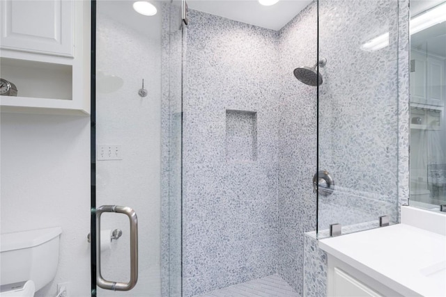 bathroom featuring toilet, a stall shower, and vanity