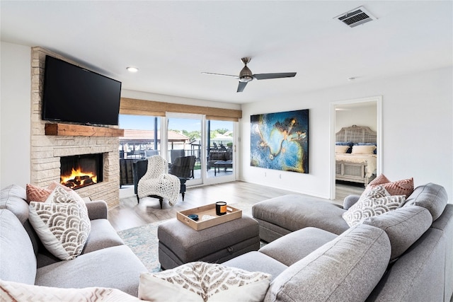 living room featuring ceiling fan, a fireplace, and light hardwood / wood-style floors