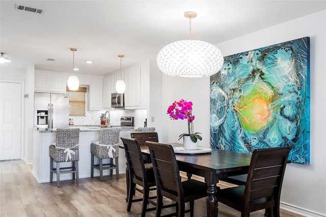 dining area with an inviting chandelier and light wood-type flooring