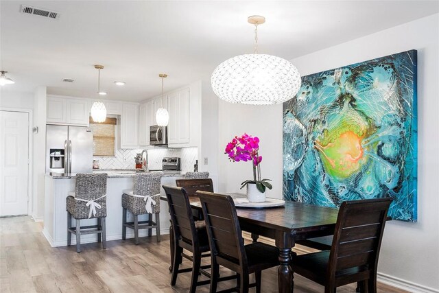 dining area featuring baseboards, visible vents, and light wood finished floors