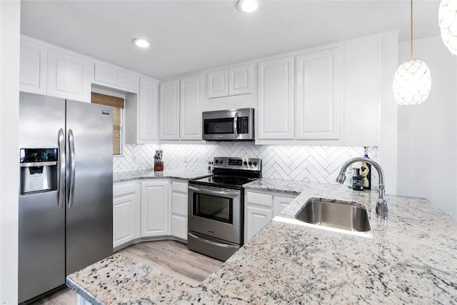 kitchen featuring hanging light fixtures, appliances with stainless steel finishes, sink, and white cabinets