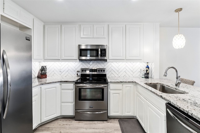 kitchen with white cabinetry, appliances with stainless steel finishes, sink, and decorative light fixtures