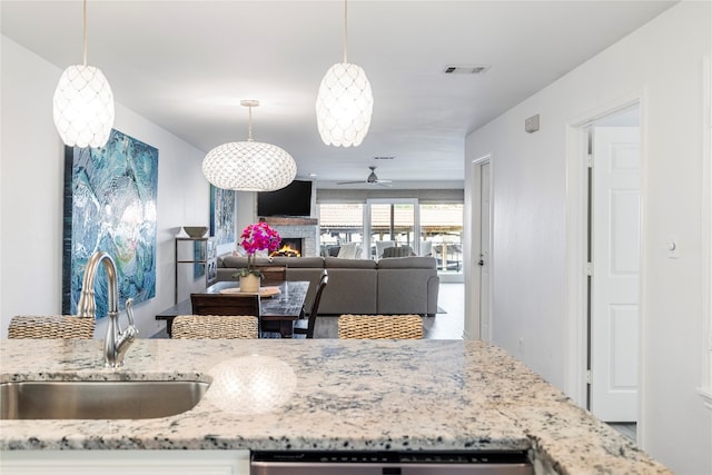 kitchen featuring dishwasher, light stone countertops, sink, and pendant lighting