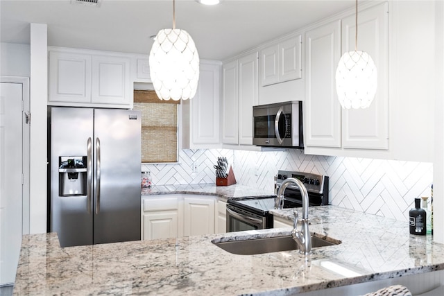 kitchen featuring white cabinetry, stainless steel appliances, light stone countertops, and pendant lighting