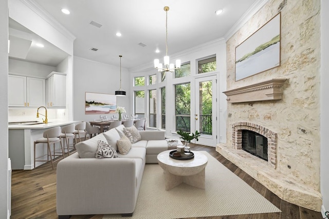 living room with a fireplace, crown molding, a chandelier, and dark hardwood / wood-style floors