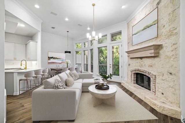 living room featuring crown molding, dark wood-type flooring, a brick fireplace, and a notable chandelier