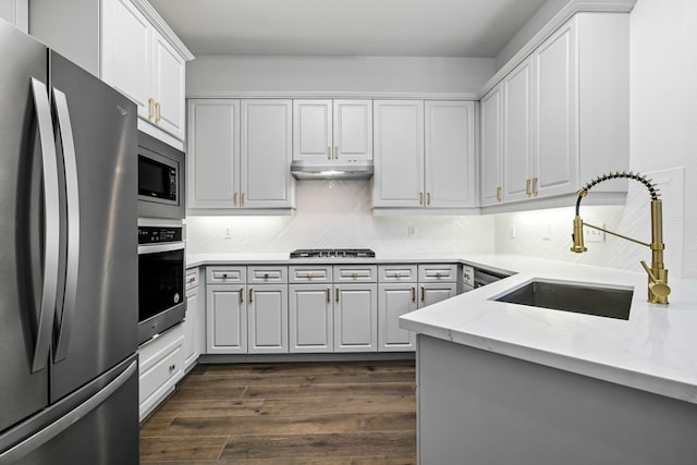 kitchen with white cabinetry, stainless steel appliances, light stone countertops, and sink