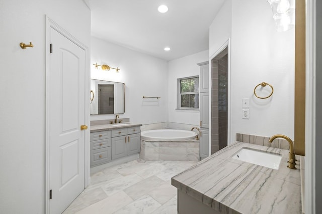 bathroom featuring a relaxing tiled tub and vanity