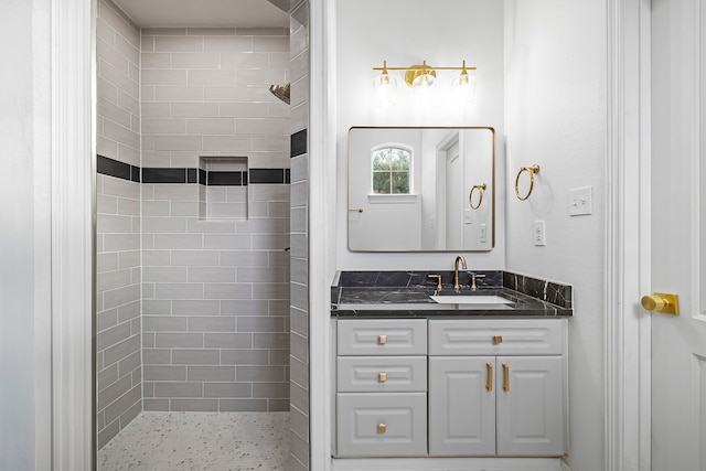 bathroom with tiled shower and vanity