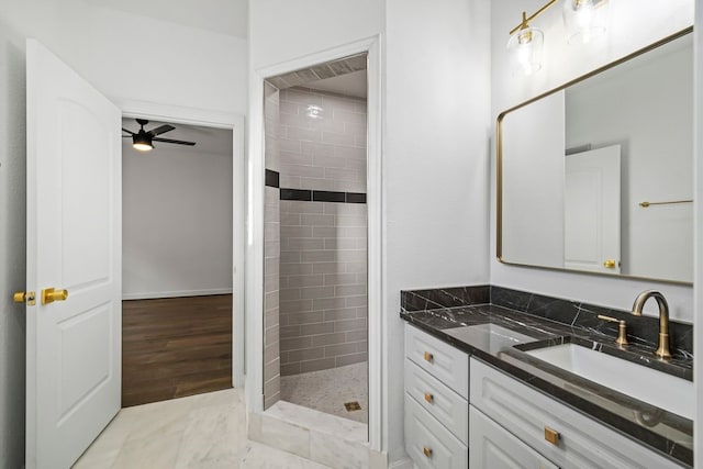 bathroom featuring ceiling fan, vanity, and a tile shower