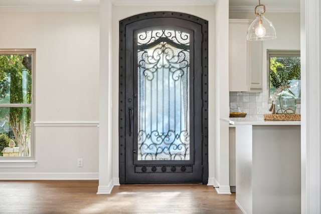 foyer entrance with light wood-type flooring, a healthy amount of sunlight, and crown molding