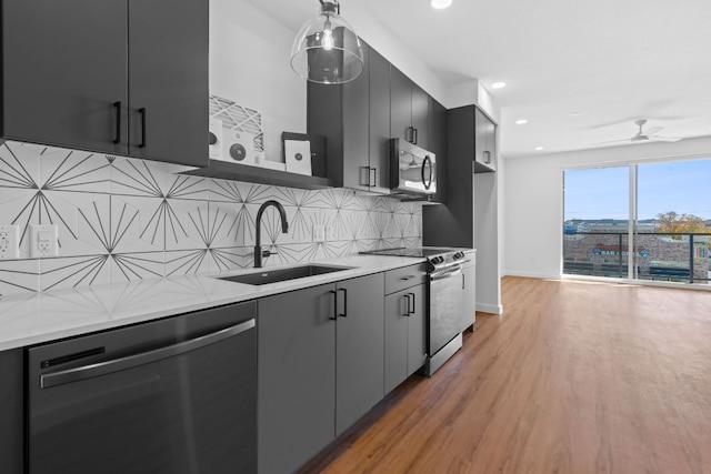 kitchen with light stone counters, stainless steel appliances, decorative backsplash, hardwood / wood-style flooring, and sink